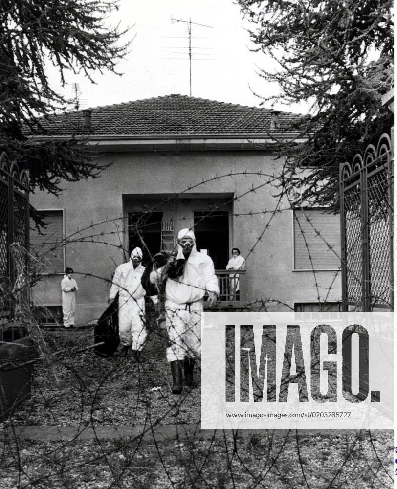 SCANPIX SWEDEN, 1976 Toxic accident in Seveso, Italy Pictured are men in white protective clothing exiting a building Seen through a rolled-up barbed wire