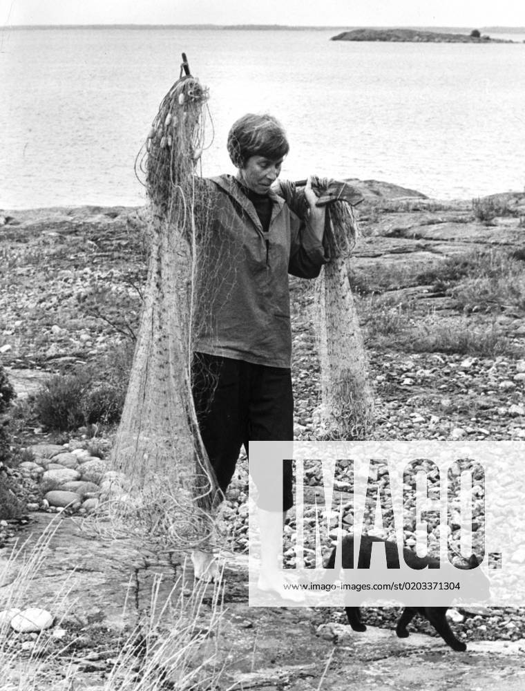 FILE 1961 07 13 Tove Jansson, author of the Moomin books, pictured at her childhood island Bredsar in the Gulf of Finland, where she owned several houses The cat Priprina follow her mistress who is handlling the fishing nets Bredsär FINLAND