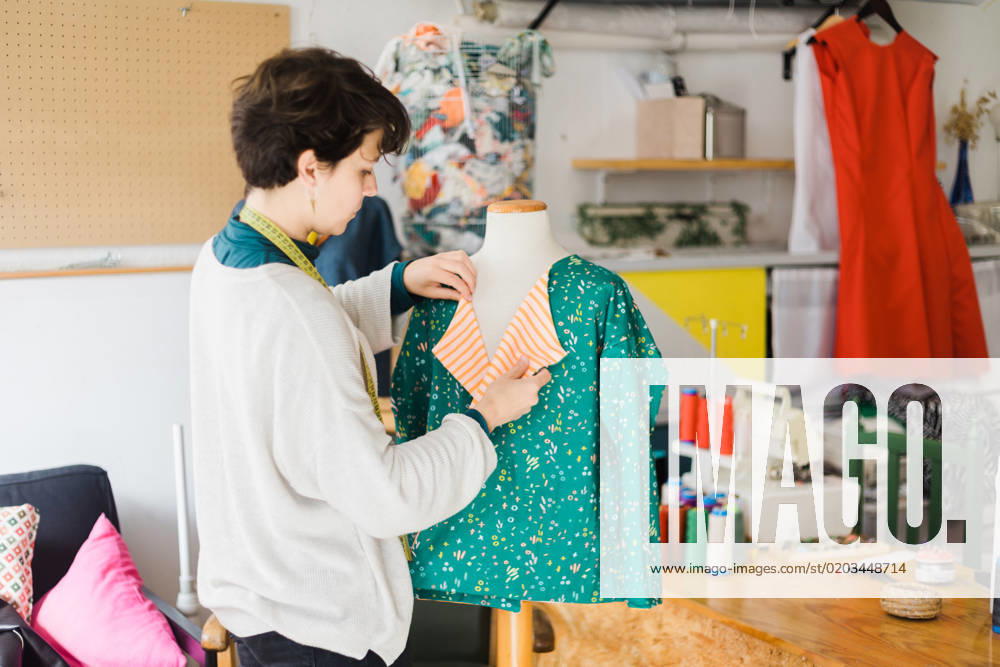 Concentrated female tailor in casual clothes with measuring tape on neck standing near mannequin while preparing clothing for work in creative studio, Model released, Property released AlbaCaro_ID12631_384063_072