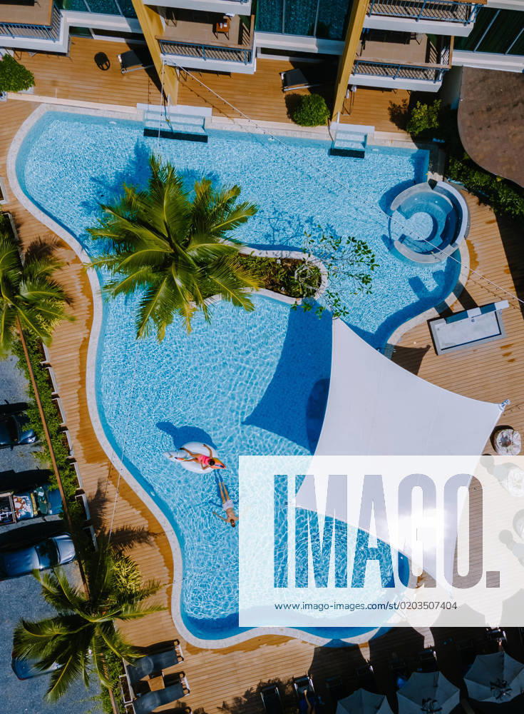 View from above at a swimming pool, couple men and women in swimming pool, drone view Drone view at the pool with palm trees, a couple of men and women in a swimming pool view from above