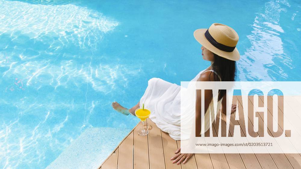 Asian women with hat with cocktail by the pool Asian women with a hat with cocktails by the pool. Women drinking cocktail by swimming pool