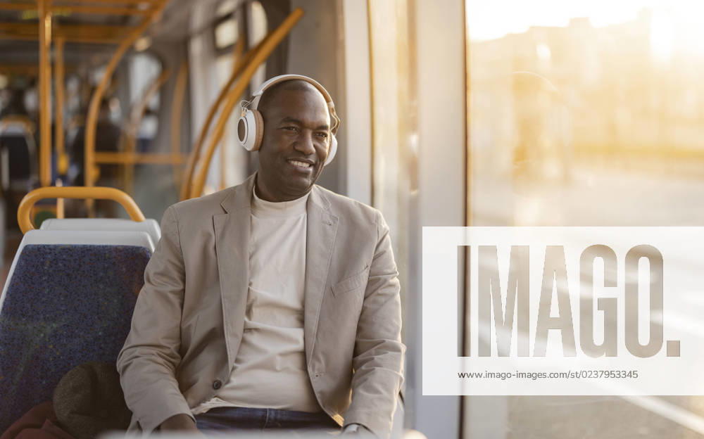 IMAGO Creative, Urban Lifestyle Smiling businessman listening to music on headphones in cable car model released, Symbolfoto, JCCMF09275