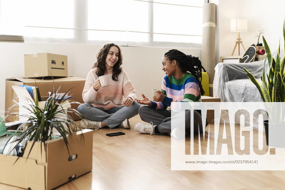 IMAGO Creative, Lifestyle, Leben in einer Wohngemeinschaft, WG Young woman and friend having coffee at new home model released, Symbolfoto property released, JCZF01173