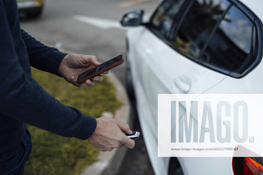 Man with mobile phone locking car with key model released, Symbolfoto, JOSEF16589