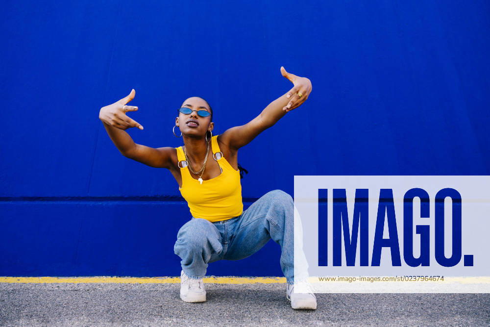 Young woman in squatting in front of blue wall model released, Symbolfoto, OIPF03073
