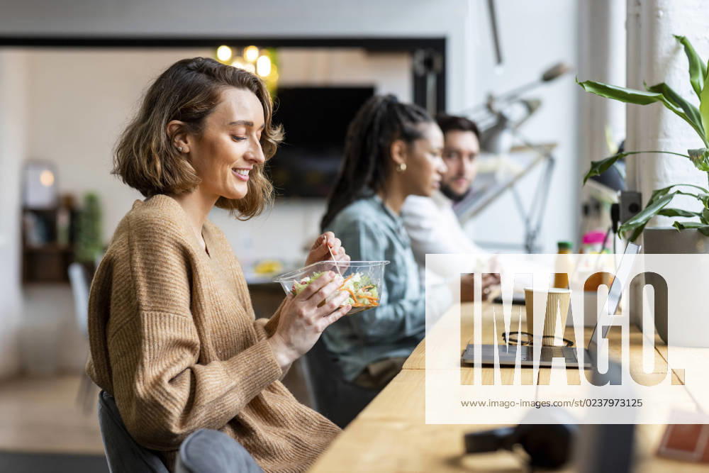 Smiling businesswoman eating salad in lunch break in office model released, Symbolfoto property released, WPEF07038