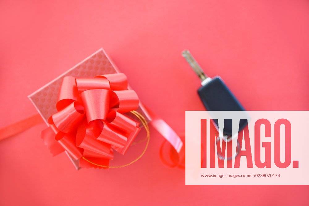 Give gift car key concept Red gift box with red ribbon bow and key car as present on red background