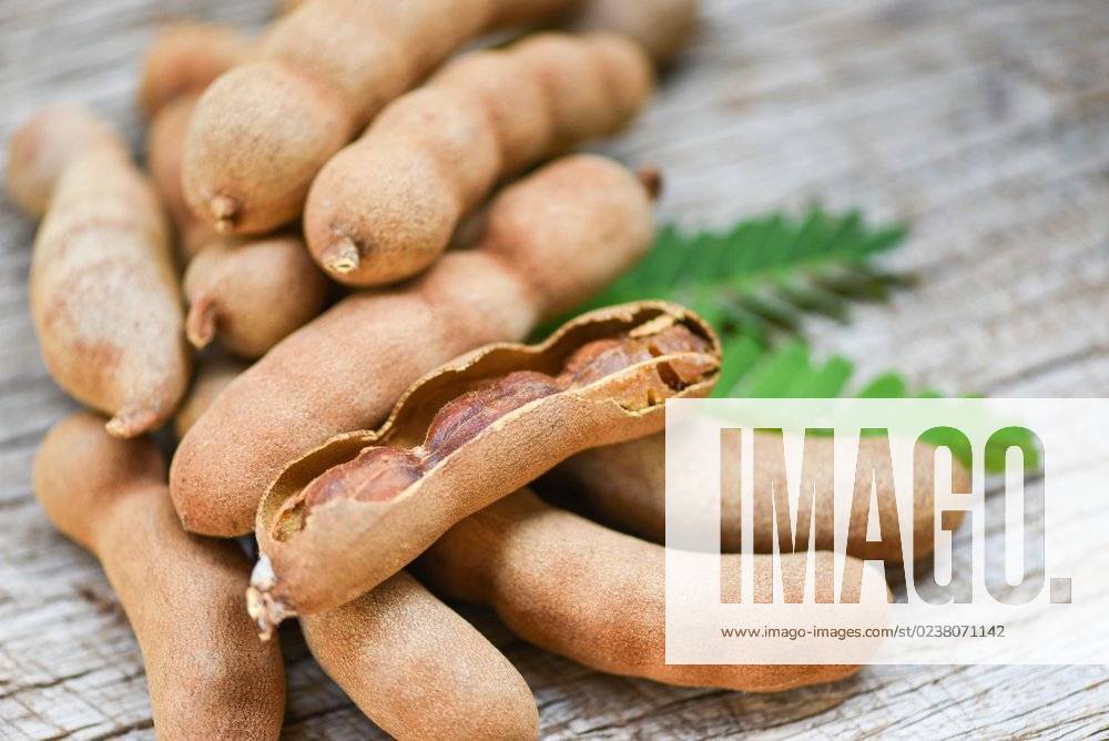Tamarind and leaves tropical fruit Sweet tamarind on wooden background; Tamarinde und verlässt tropisch Frucht suesse Tamarinde am hölzern Hintergrund IST_23395_10117
