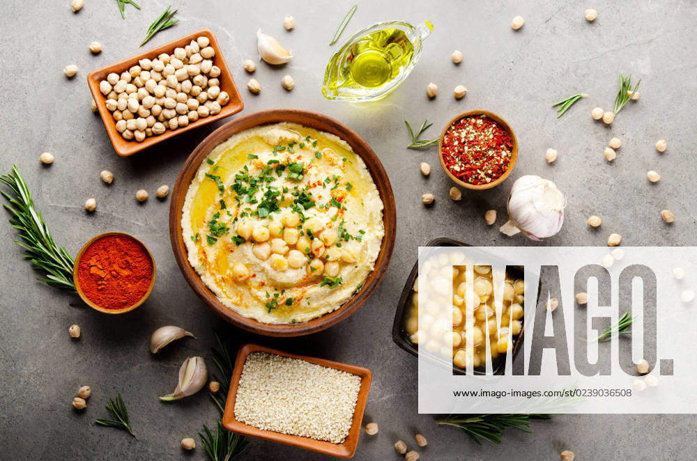 IMAGO Creative, Food, Hummus Hummus topped with chickpeas, olive oil and green coriander leaves on stone table with different spices aside. Flat lay Hummus topped with chickpeas, olive oil and green coriander leaves on stone table with different spices aside. Flat lay