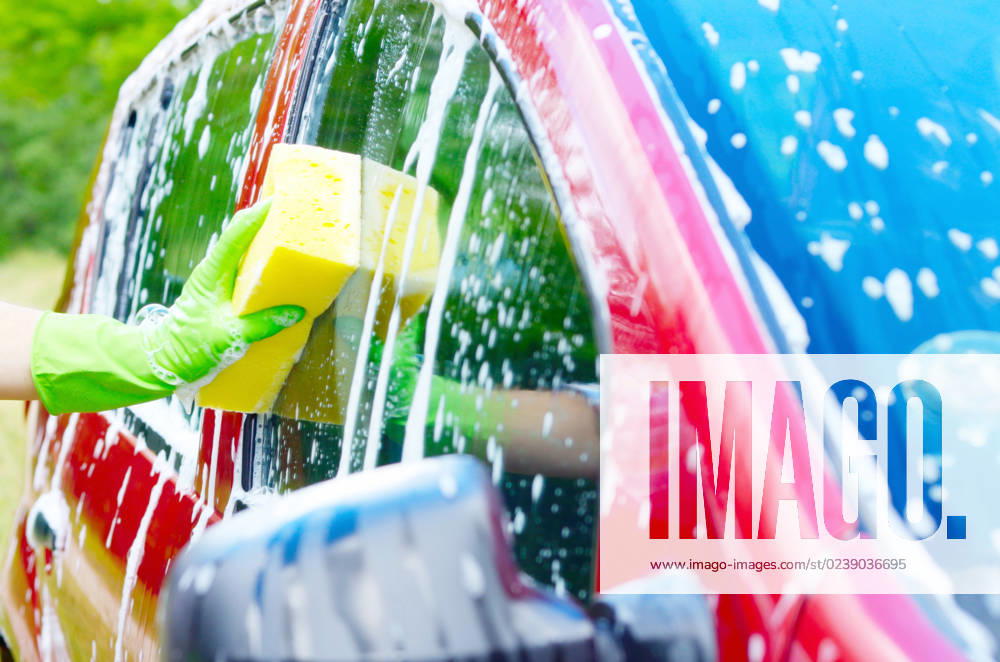 Male hand in green glove with yellow sponge washing car window Male hand in green glove with yellow sponge washing car window