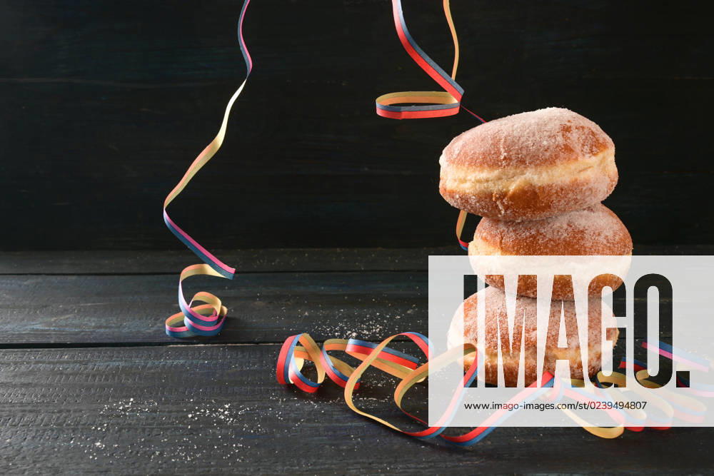 Stacked Berliner doughnuts or Krapfen and some party streamers against a dark rustic background, often served on New Year and carnival, copy space, selected focus Stacked Berliner doughnuts or Krapfen and some party streamers against a dark rustic background, often served on New Year and carnival, copy space, selected focus, narrow depth of field