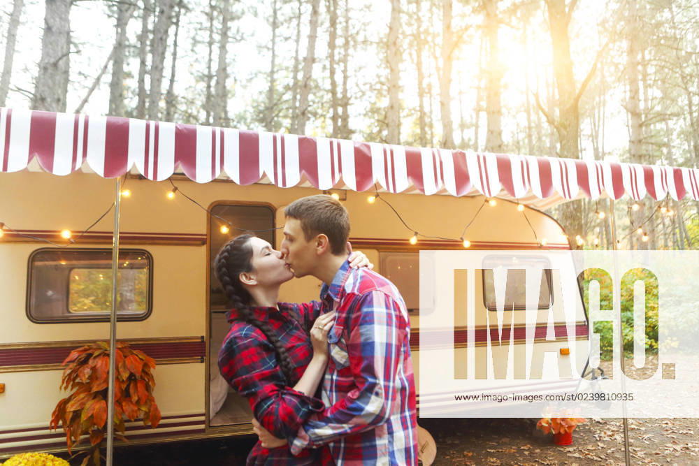 Portrait of romantic couple smiling while holding hands near house on wheels outdoors Portrait of romantic couple man and woman smiling while hugging near house on wheels outdoors ,model released, Symbolfoto