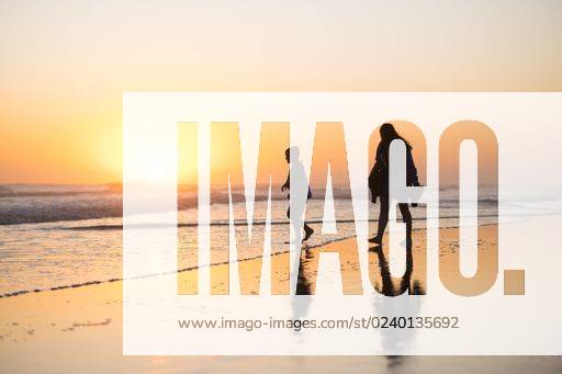 A silhouette of a person walking down a sandy beach, illuminated by the soft light of a sunset over the ocean *** einer Schattenriss des einer person Spazierengehen nieder einer sandiger beach, beleuchtet indem der weich Licht des einer Sonnenuntergang trueber der Ozean 15030708 ,model released, Symbolfoto