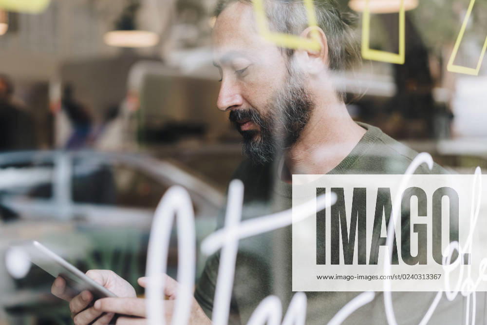 IMAGO Creative, Urban Lifestyle Mature man using tablet PC in cafe seen through glass model released, Symbolfoto property released, JOSEF17195