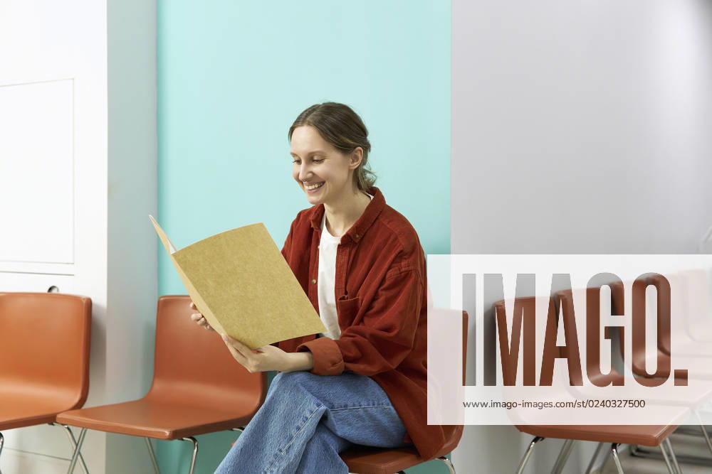Happy woman reading medical results sitting on chair at clinic model released, Symbolfoto property released, SANF00037