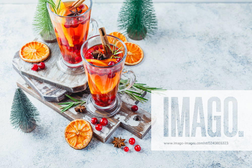 Orange and cranberry drinks with orange slices and spices. Hot drinks for winter and Christmas Hot tea with orange slices and cranberries in glass tall glasses. Hot drinks for winter and Christmas. Place for text.