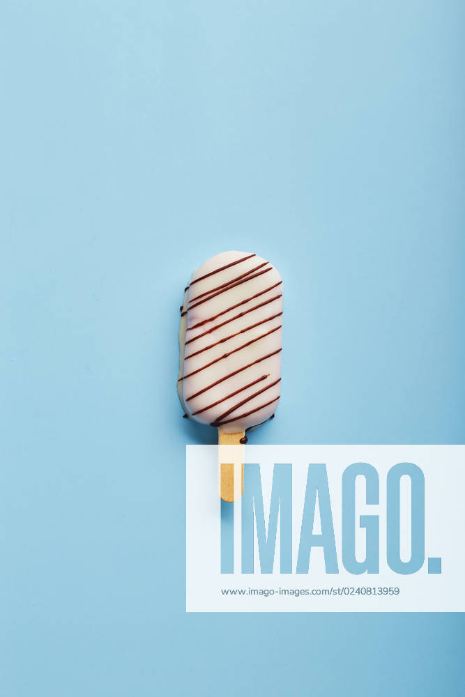 Mousse dessert with fruit flavors in the form of popsicle ice cream on blue background. Mousse dessert with fruit flavors in the form of popsicle ice cream covered with white chocolate on blue background.