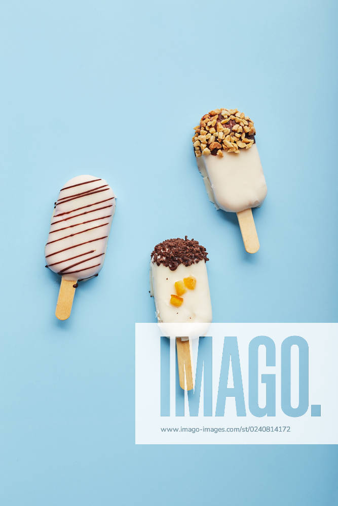 Mousse dessert with fruit flavors in the form of popsicle ice cream on blue background. Mousse dessert with fruit flavors in the form of popsicle ice cream covered with white chocolate on blue background.