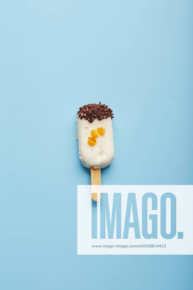 Mousse dessert with fruit flavors in the form of popsicle ice cream on blue background. Mousse dessert with fruit flavors in the form of popsicle ice cream covered with white chocolate on blue background.