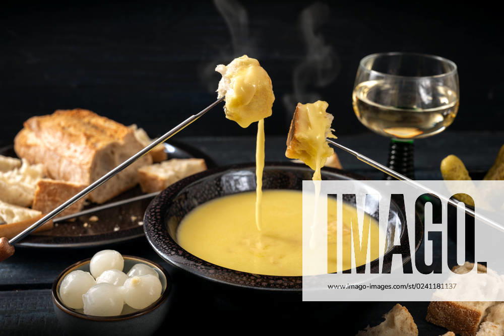 IMAGO Creative: Herbst, Kulinarische Klassiker Swiss cheese fondue with bread, pickles and wine, the festive dinner is often served at new year, dark rustic background, copy space, selected focu Swiss cheese fondue with bread, pickles and wine, the festive dinner is often served at new year, dark rustic background, copy space, selected focus, narrow depth of field