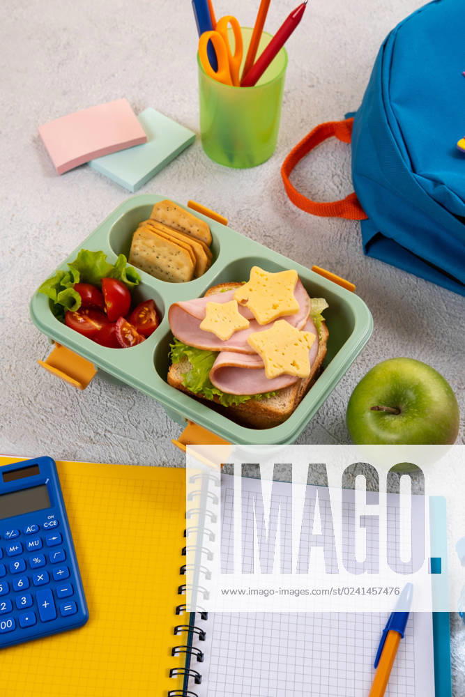 Healthy school lunch box with sandwich and salad on the workplace near backpack. School supplies, books, apple and a bottle of water. Healthy school lunch box with sandwich and salad on the workplace near backpack. School supplies, books, apple and a bottle of water.