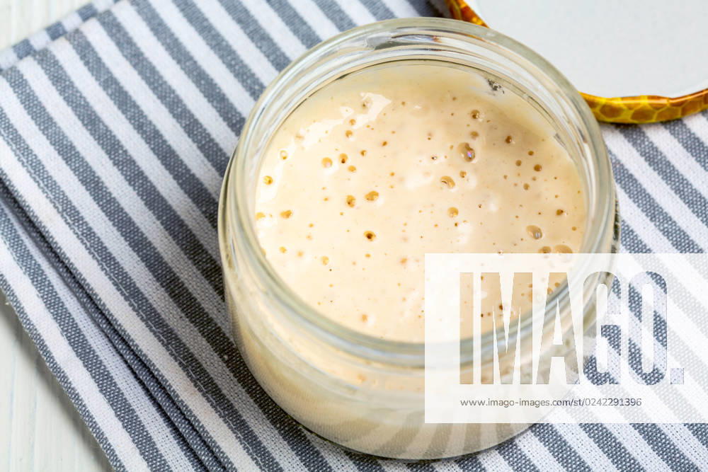 Mature sourdough in jar. Artisanal wheat sourdough starter. Top view of glass jar with sourdough starter close up,selective focus. Copy space.