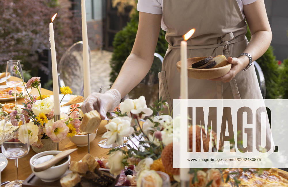Wedding table for guests, decorated with candles, are served with cutlery and crockery and covered with yellow tablecloth Wedding. Banquet. Chairs and a table for guests, decorated with candles, are served with cutlery and crockery and covered with yellow tablecloth. Waiter setting table stands on a green lawn in the backyard banquet area ,model released, Symbolfoto