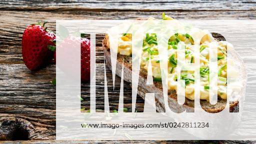 Bread with eggs salad and chives and two strawberry on rustic old wooden table with copy space *** Brot mit Eier Salat und Schnittlauch und Zwei Erdbeere am Rustikal Alte hölzern Tisch mit Kopie Weltraum 10534983