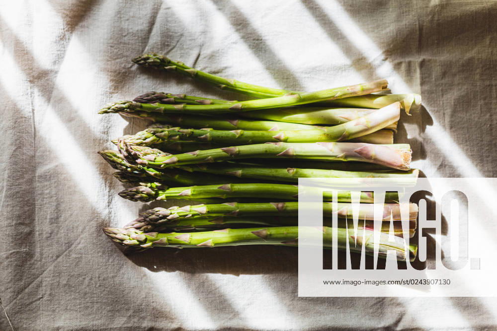 IMAGO Creative: Food, Spargel Green fresh asparagus lies on a linen tablecloth,sunny light . Öhringen, Baden-Württemberg, Germany R_DVHK230411-1169227-01