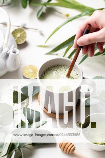A vertical shot of Green tea latte with milk in a white cup with green leaves and wooden spoon *** einer hoch erschossen des Grün Tee latte mit Milch ÊIn einer weiß Tasse mit Grün verlässt und hölzern löffeln 201073