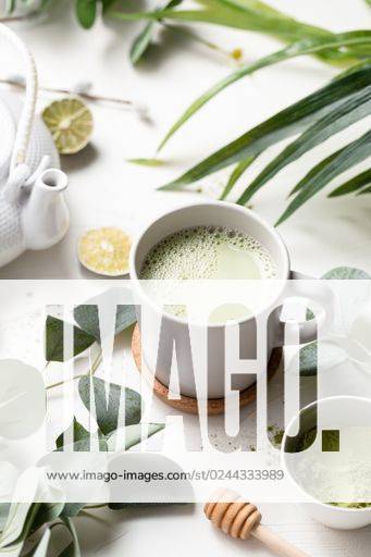 A vertical shot of Green tea latte with milk in a white cup with green leaves and wooden spoon *** einer hoch erschossen des Grün Tee latte mit Milch ÊIn einer weiß Tasse mit Grün verlässt und hölzern löffeln 201075