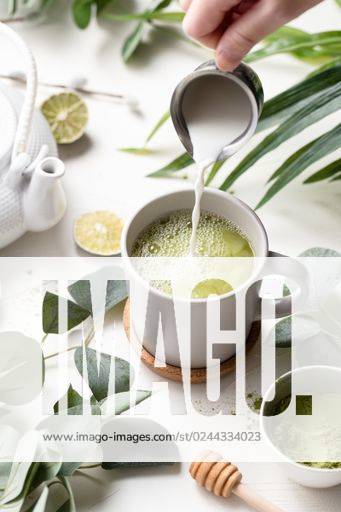 A vertical shot of Green tea latte with milk in a white cup with green leaves and wooden spoon *** einer hoch erschossen des Grün Tee latte mit Milch ÊIn einer weiß Tasse mit Grün verlässt und hölzern löffeln 201079