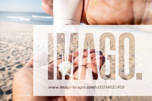 IMAGO Creative, Jahreszeit Sommer, Sonnenschutz A man applying sunscreen cream to his hands on the beach *** einer Mann applying sunscreen Creme an seinem Hände am der Strand 2209737