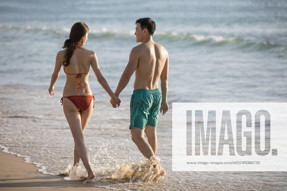 Happy young Chinese couple walking on beach Beijing China