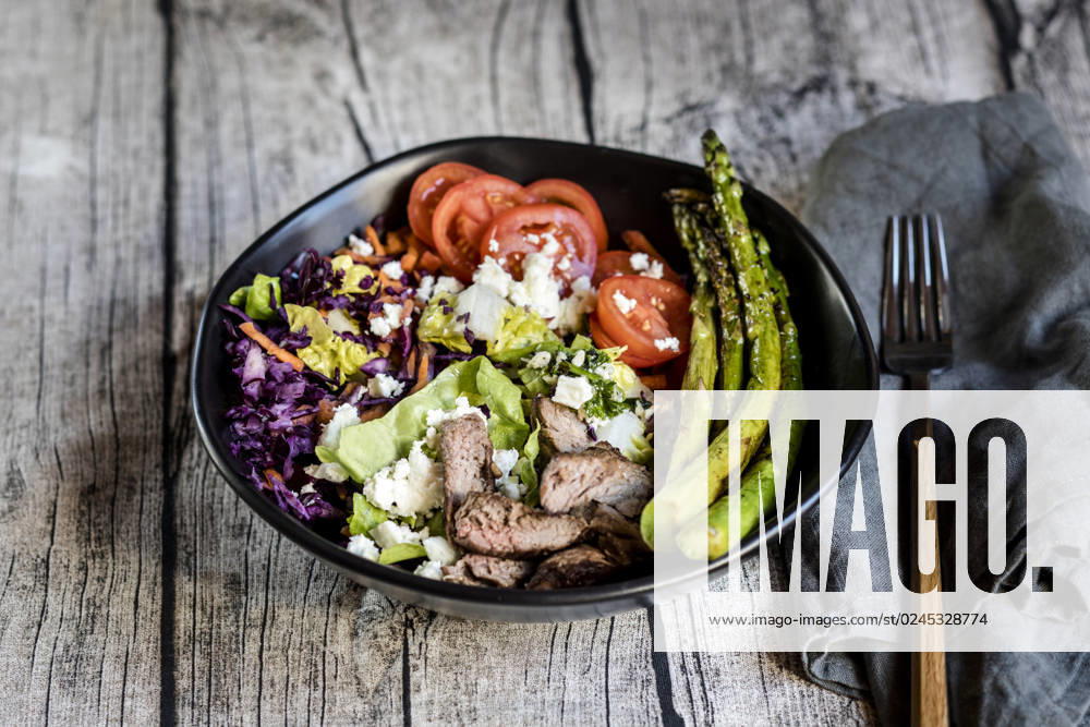 Bowl of salad with steak, asparagus, tomatoes, shredded red cabbage, lettuce and feta cheese, SBDF04606