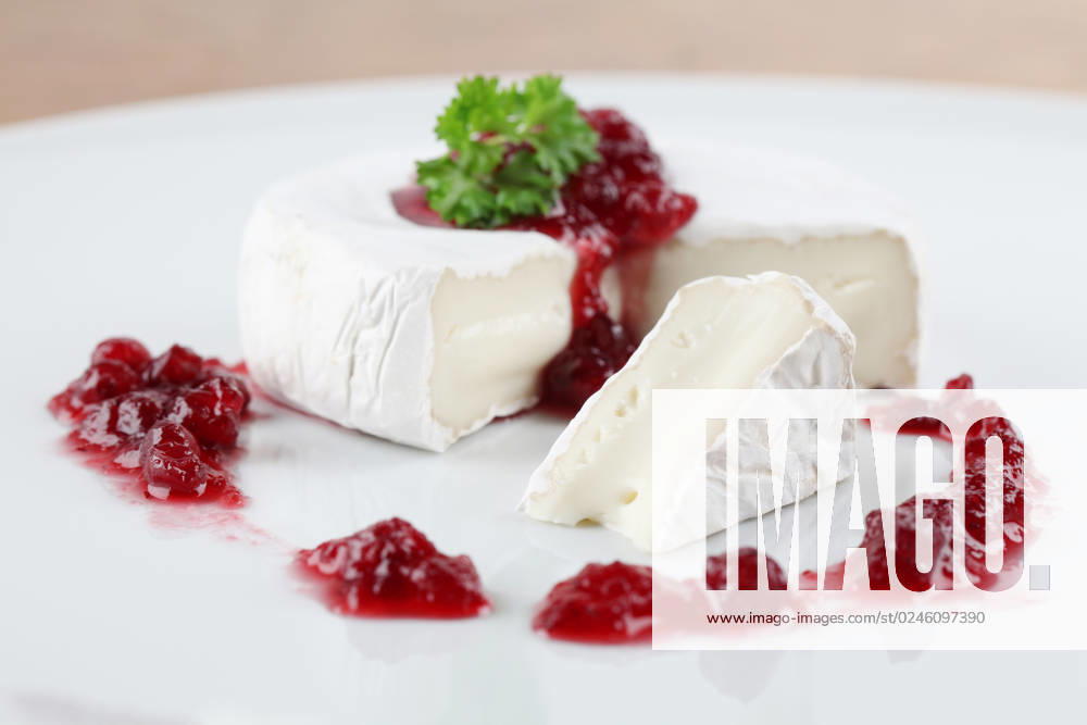 Camembert with cranberry jam and parsley on white plate. Shallow dof