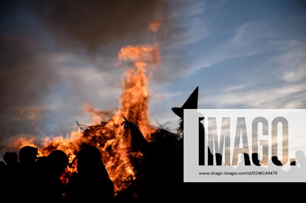 Weimarer Land Bergern A girl dressed as a witch with a witchs hat stands out as a silhouette in front of a traditional fire for Walpurgis Night