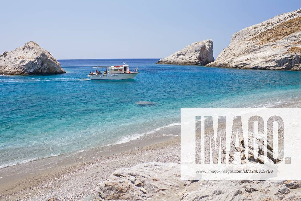 A boat transferring tourists arrives at the remote Katergo beach, Folegandros island, Greece