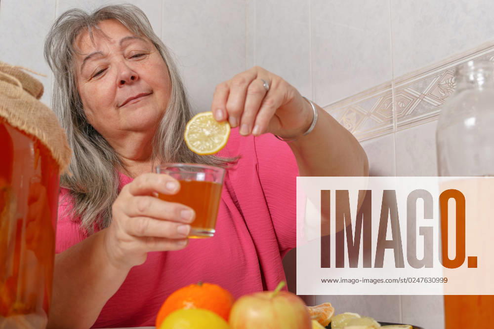 Woman drinking a glass of fermented kombucha tea with natural lime older white-haired woman drinking a glass of fermented kombucha tea with natural lime ,model released, Symbolfoto