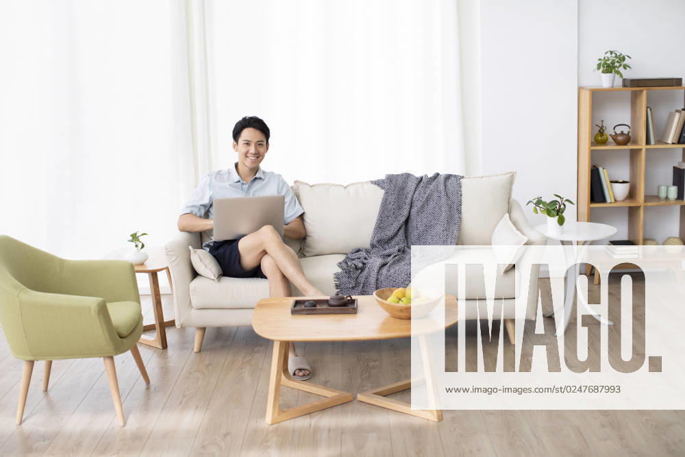 Happy young Chinese man using laptop in living room Beijing China