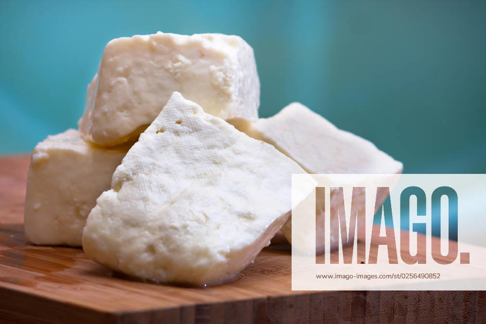 Big slices of Curd cheese on cutting board.