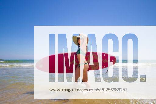 A Hispanic woman wearing swimwear while holding a surfboard on the beach *** einer hispanisch Frau wearing Badekleidung wärend haltend einer Surfbrett am der Strand 6936223 ,model released, Symbolfoto