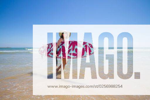 A Hispanic woman wearing a swim wear while holding a surf board on the beach *** einer hispanisch Frau wearing einer Schwimm tragens wärend haltend einer Brandung Brett am der Strand 6936229 ,model released, Symbolfoto