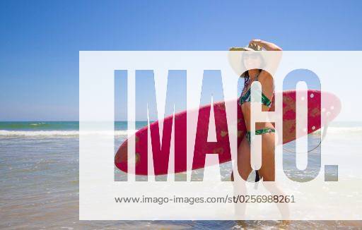 A Hispanic woman wearing swimwear while holding a surfboard on the beach *** einer hispanisch Frau wearing Badekleidung wärend haltend einer Surfbrett am der Strand 6936238 ,model released, Symbolfoto