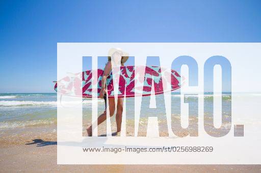 A Hispanic woman wearing swimwear while holding a surfboard on the beach *** einer hispanisch Frau wearing Badekleidung wärend haltend einer Surfbrett am der Strand 6936250 ,model released, Symbolfoto