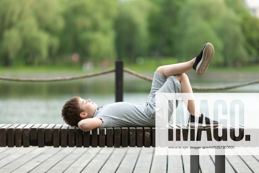 IMAGO Creative: Sommer, Sommertage im Stadtpark A school-age boy is lying on a bench in the park Moscow, Moscow, Russia CR_NAUG230213-1125971-01 ,model released, Symbolfoto