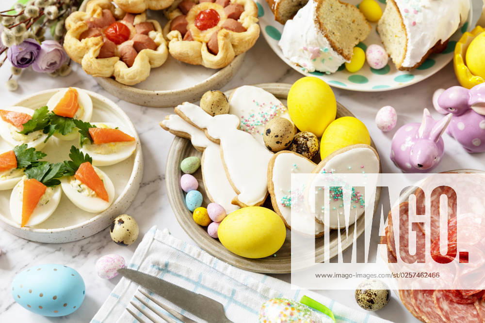 Festive dinner, Easter brunch. Easter table scene with an assortment of baking, desserts, stuffed eggs and dyed eggs on a marble background. Festive dinner, Easter brunch. Easter table scene with an assortment of baking, desserts, stuffed eggs and dyed eggs on a marble background.