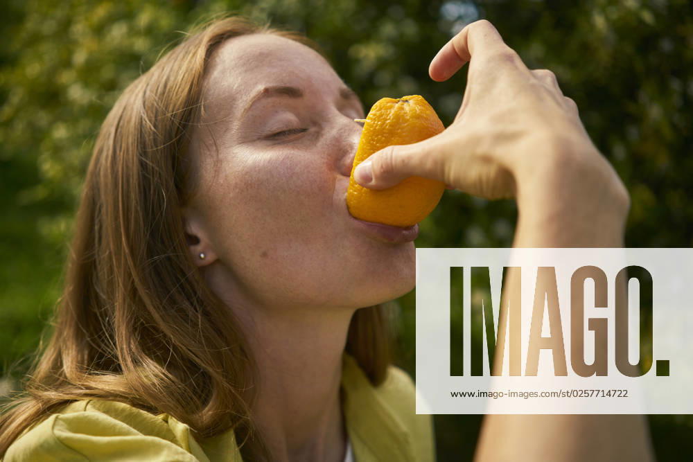 Woman with eyes closed eating fresh orange at orchard model released, Symbolfoto property released, ANNF00241