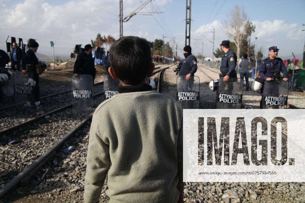Refugee boy in Greece Refugees at the Balkan Route to the Border between Greece and Macedonia Greek Macedonian Border at Refugee camp Idomeni on 01 03 2016 a Kleiner Boy Child is before Greek Police officers Police