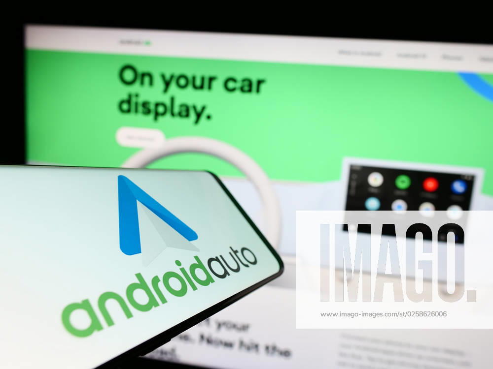 Cellphone with logo of mobile app Android Auto (Google) on screen in front of website. Stuttgart, Germany - 03-14-2023: Cellphone with logo of mobile app Android Auto (Google) on screen in front of website. Focus on center-right of phone display.
